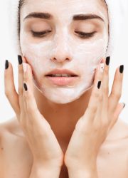 Beauty Skin Care Concept - Beautiful Caucasian Woman Face Portrait applying cream mask on her facial skin white background.